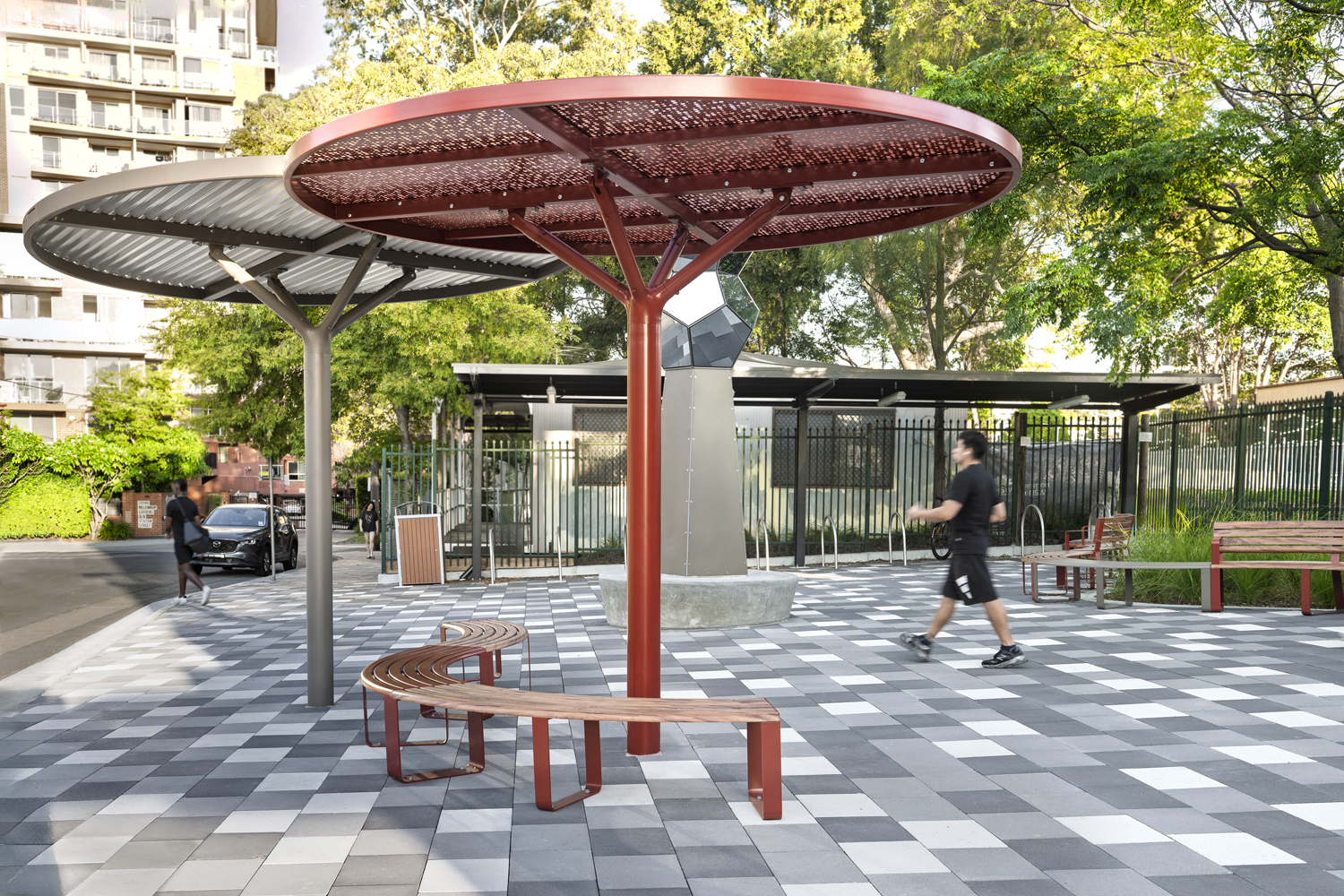 ChillOUT Tree in Pioneer Red with Champagne perforated roof, and Textura Jasper with solid Shale Grey roof. Linea Curved Benches with aluminium Spotted Gum battens, Pioneer Red frames.