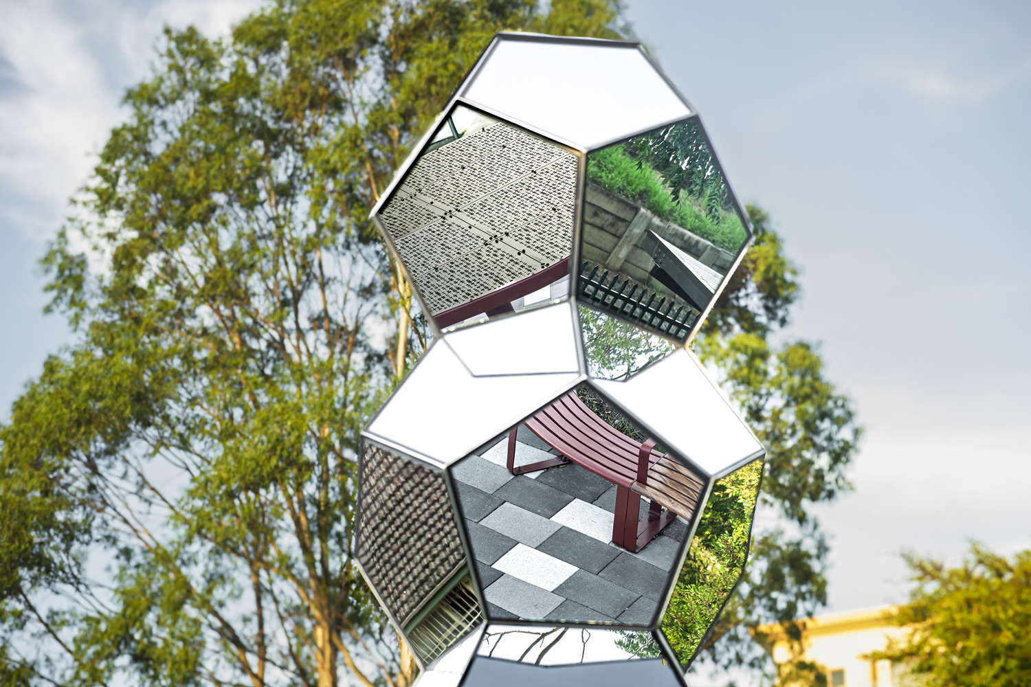 Sculpture reflects street furniture below.