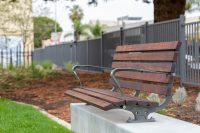 Plinth-mounted Mall DDA Seat with Jarrah battens and frames in tailored colour Metropolis Storm Pearl grey.