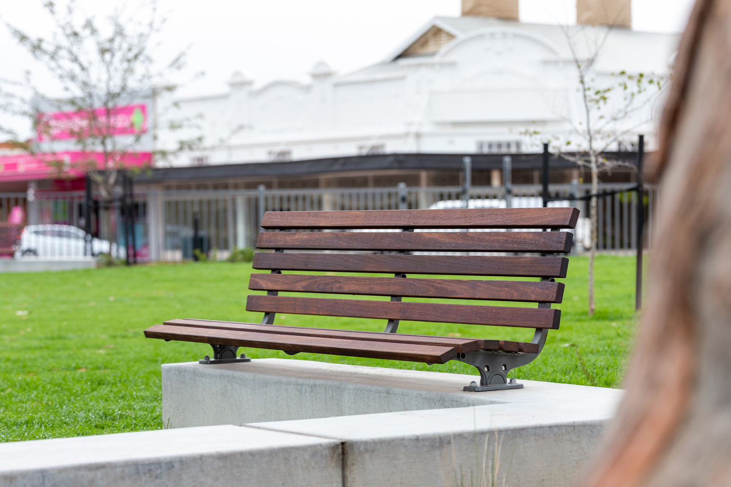 Plinth-mounted Mall DDA Seat with Jarrah battens and frames in tailored colour Metropolis Storm Pearl grey.