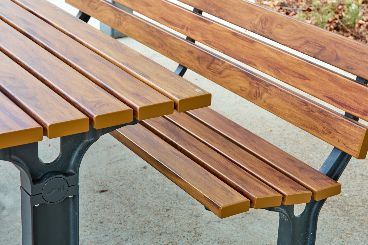 Johnson Park. Wooden park bench with brown slats and a gray metal frame on a gravel surface.
