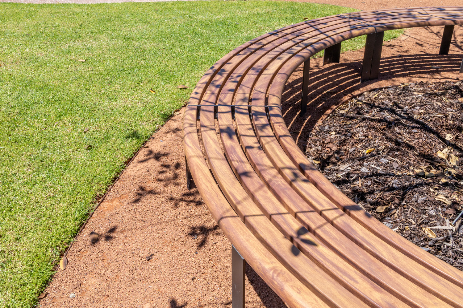 Linea Curved Bench (LIB6-C) with aluminium woodgrain Spotted Gum battens, Textura Dark Bronze frame.